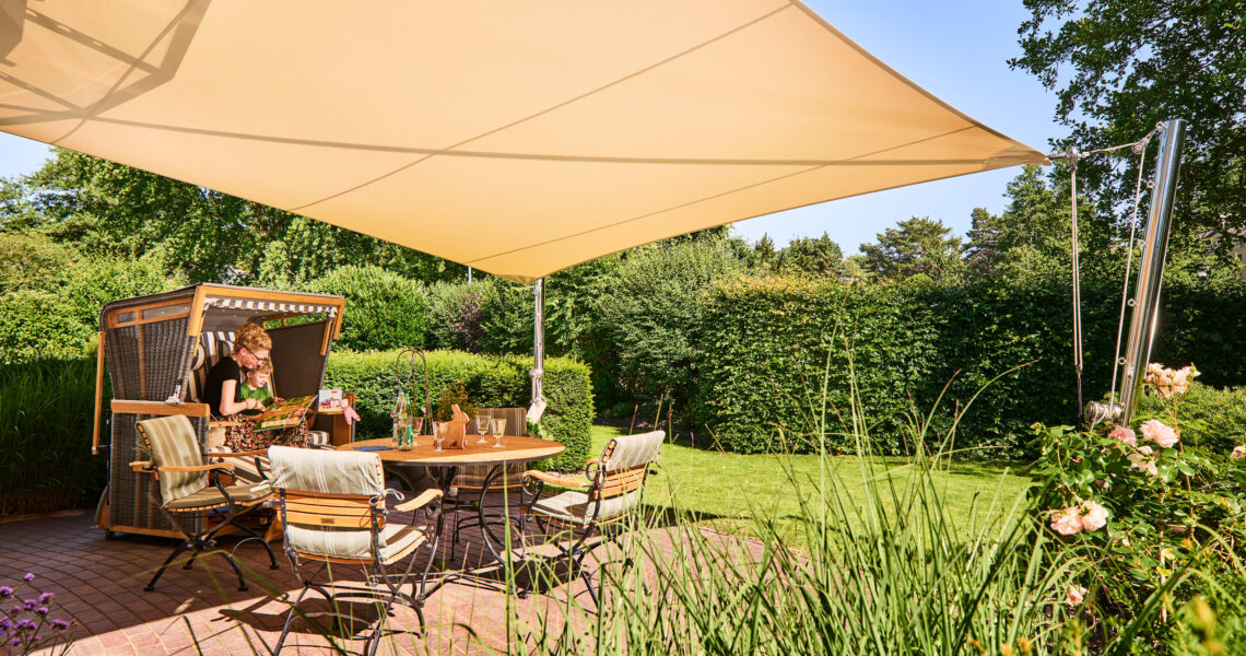 SunFurl RM Sonnensegel mit Edelstahl-Masten über gemütlicher Terrasse